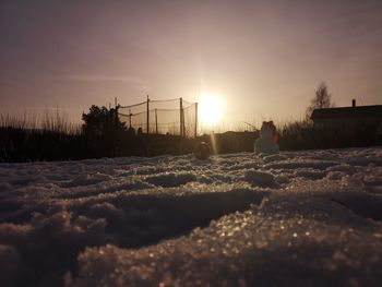 Scenic view of snow covered land against sky at sunset