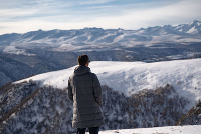 Rear view of man standing on snowcapped mountain