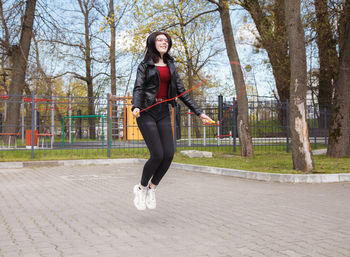 Full length portrait of young woman standing on footpath