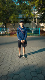 Portrait of young man standing on footpath