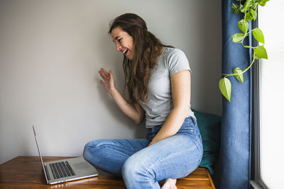 Smiling portrait of individual woman facetiming on laptop from home