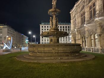 Statue in city against sky at night