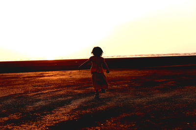 Full length of woman standing on field against sky during sunset