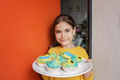 Ukrainian girl for whom neighbors brought cupcakes with cream in yellow and blue colors for brunch