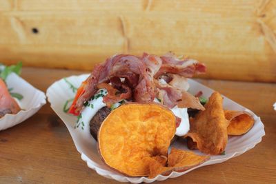 Close-up of potatoes with bacon in plate on wooden table