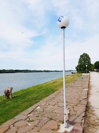 Street light by lake against sky