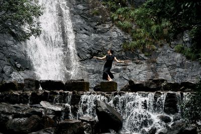 Rear view of man standing against waterfall