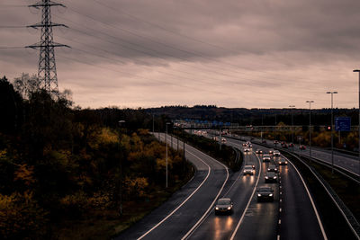 Vehicles on road against sky at sunset