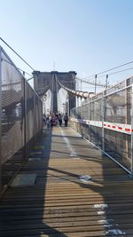 People on footbridge in city against clear sky