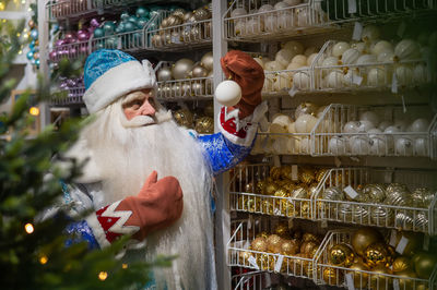 Santa holding bauble while standing in store