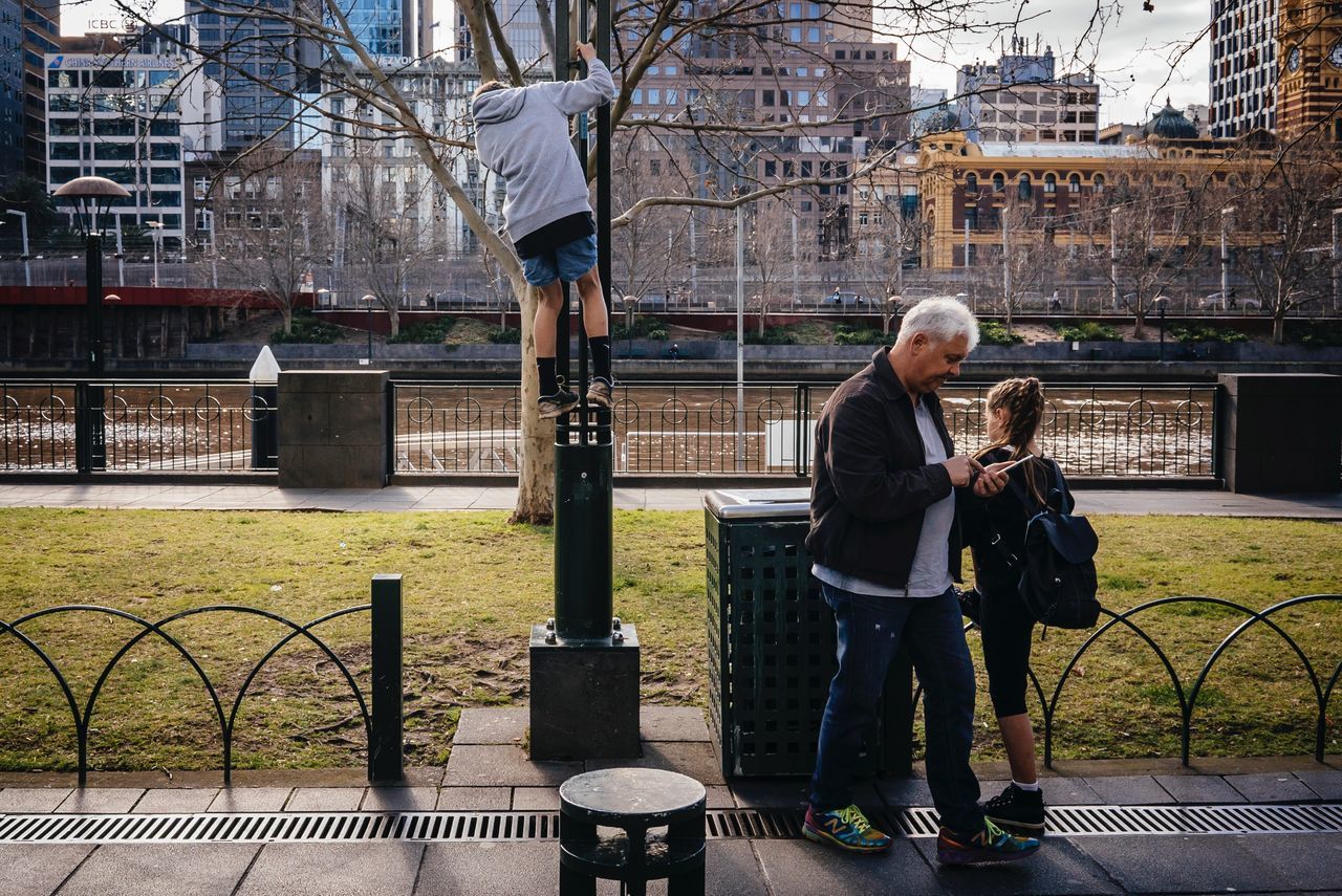 full length, city, architecture, building exterior, built structure, tree, casual clothing, holding, togetherness, bare tree, park - man made space, park bench, person, day, city life, outdoors