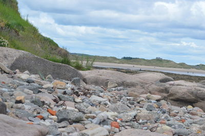 View of rocky beach against cloudy sky