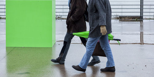 Low section of men walking on footpath during rainy season