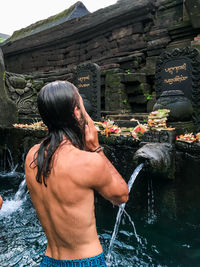 Shirtless man standing in water at temple