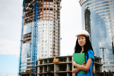 Female architect standing against incomplete building