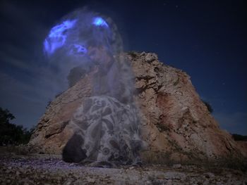 Low angle view of rock formation against sky at night