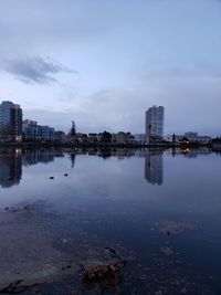 River by buildings against sky at dusk