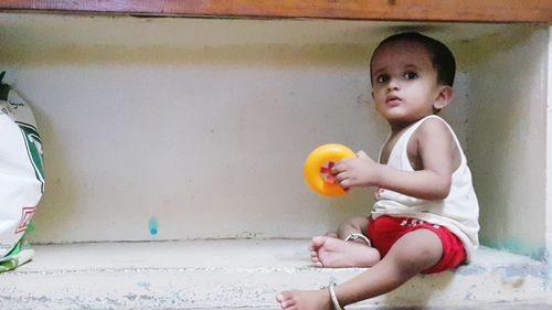 Portrait of cute boy sitting on wall