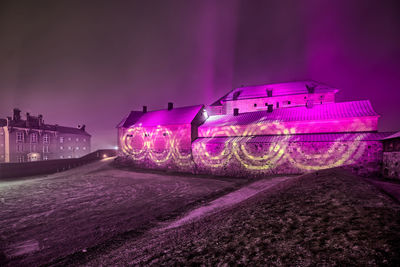 Illuminated light painting on building against sky at night