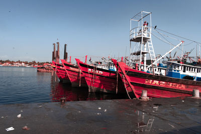 Boats moored at harbor against clear sky