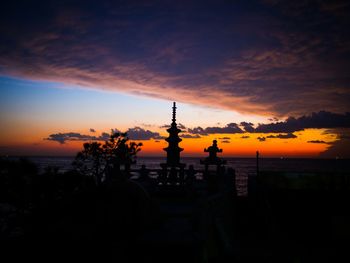 Silhouette haedong yonggung temple by sea against cloudy sky at sunrise