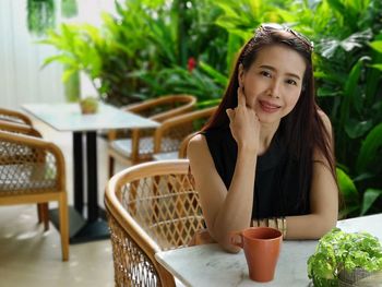 Portrait of smiling mature woman with coffee cup sitting in cafe