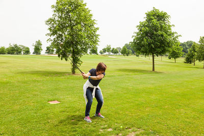 Full length of woman playing golf on land against clear sky