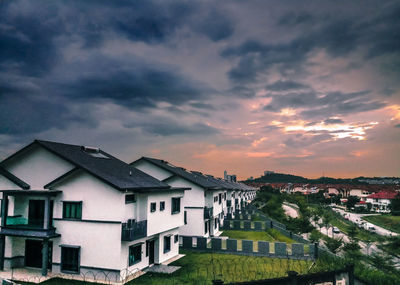 Houses in town against sky at sunset