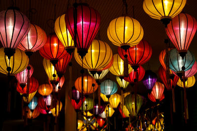 Low angle view of illuminated colorful lanterns hanging for sale at market
