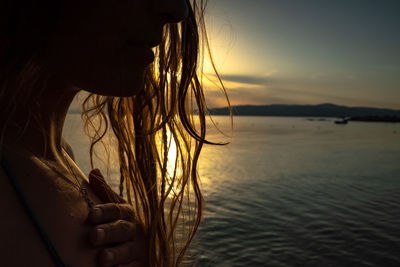 Rear view of woman in sea against sky during sunset