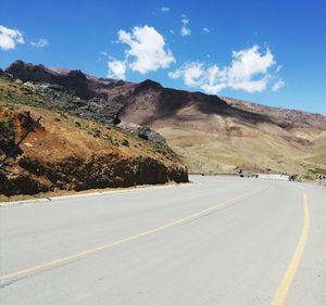 Scenic view of road by mountains against sky