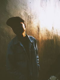 Man looking away while standing against wall