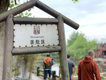 Rear view of man standing on wooden sign