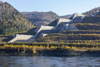 Scenic view of river by mountains against clear sky