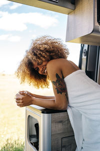 Relaxed african american female with mug of hot drink and chilling inside modern rv in summer morning