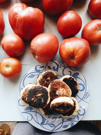 High angle view of roasted food by tomatoes on table