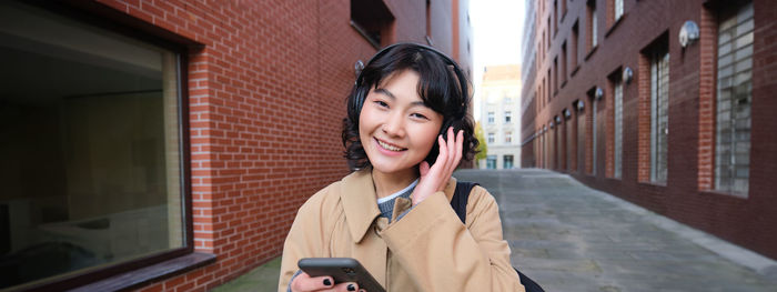 Young woman looking away while standing in city