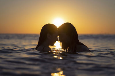 Portrait of friends at sea against sky during sunset