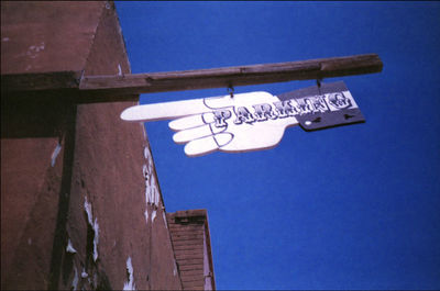 Low angle view of information sign against clear blue sky