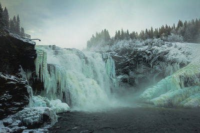 Scenic view of waterfall in forest against sky