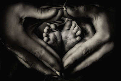 Cropped image of parents hand making heart shape around baby feet