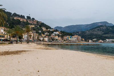 Scenic view of beach by city against sky