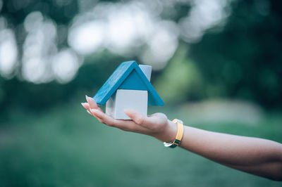 Cropped hand of woman holding model home in park