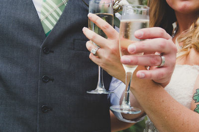 Midsection of newlywed couple holding champagne flutes at wedding ceremony