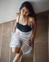 Portrait of beautiful young woman sitting on staircase