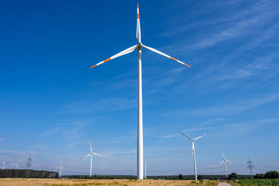 Windmills on field against blue sky