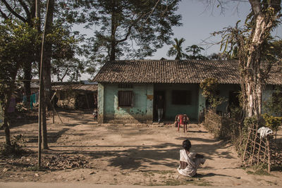 Rear view of woman sitting outside house