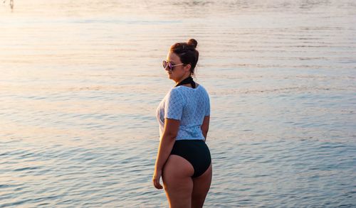 Rear view of woman standing in swimwear at beach