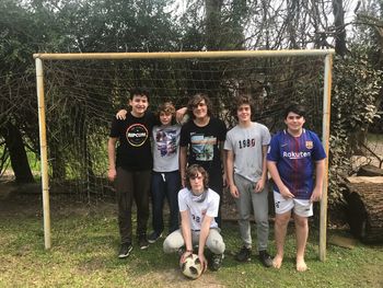 Full length portrait of friends standing by tree