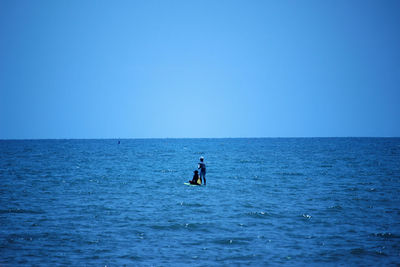 Man in sea against clear blue sky